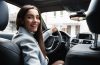 Motorista em um carro sorrindo enquanto trabalha como Uber para Mulheres