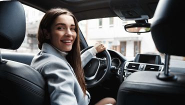 Motorista em um carro sorrindo enquanto trabalha como Uber para Mulheres