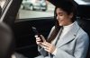 Passageira de Uber sorrindo com celular nas mãos durante viagem