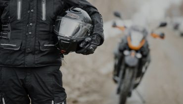Piloto de Uber Moto parado como capacete na mão e moto atrás